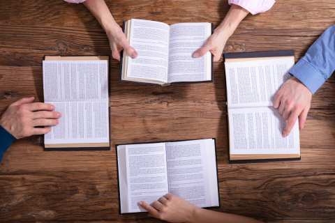 Hands holding open books on a table